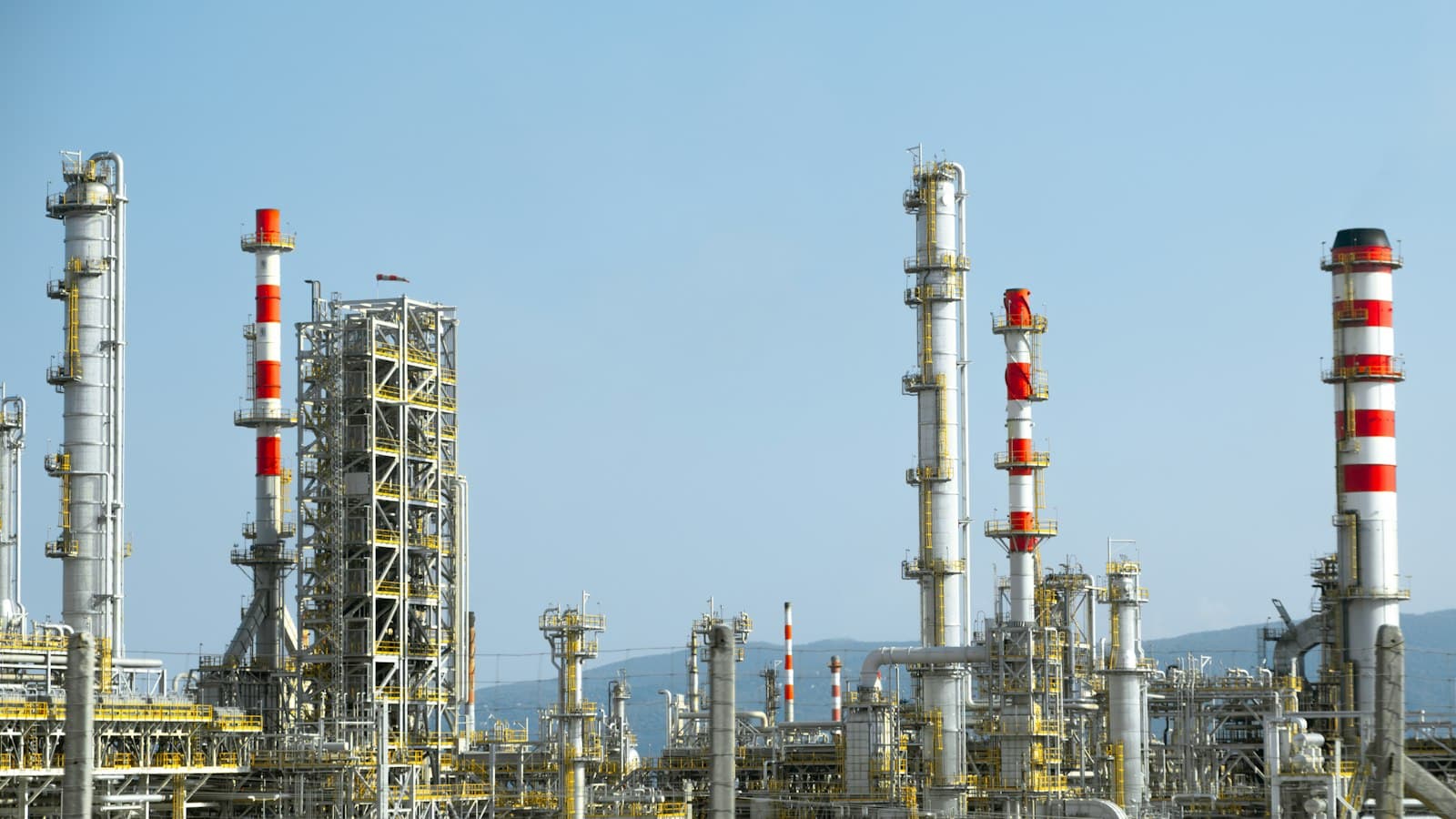 Refinery towers and red-and-white chimneys against a clear sky