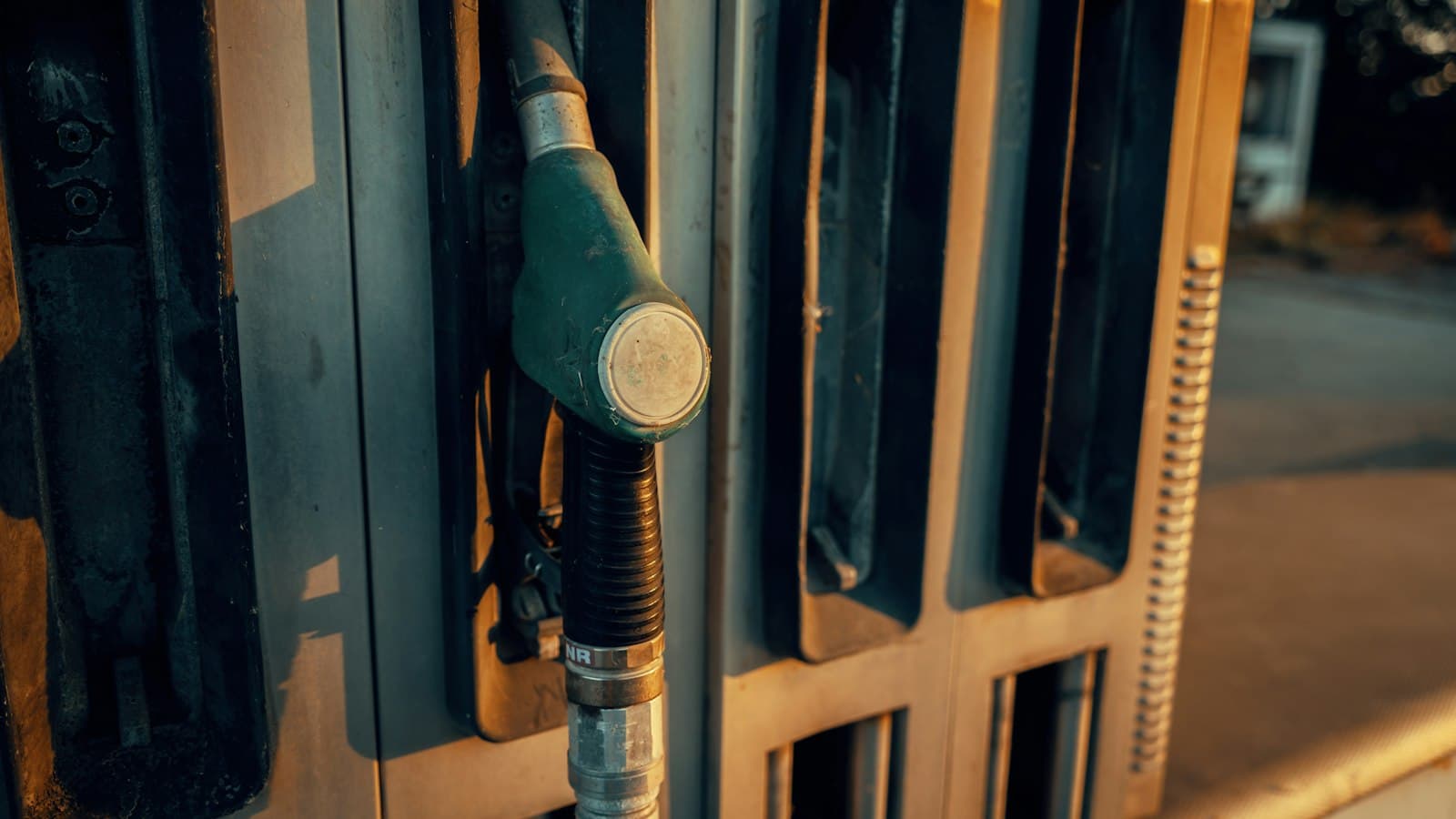 A fuel pump nozzle resting in its holder at a petrol station