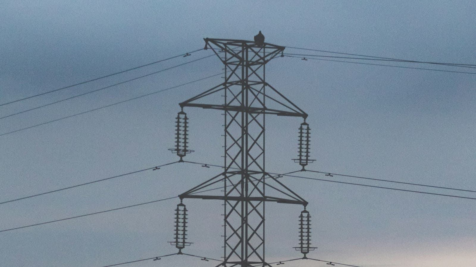 An electricity transmission pylon against an evening sky in Kampala